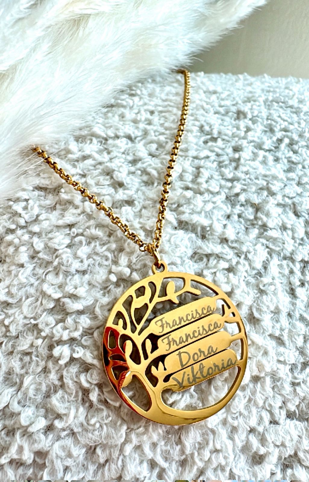 Gold necklace with a tree-shaped pendant on a textured white surface
